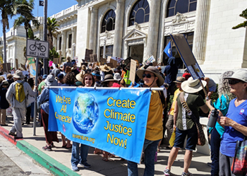 UUCV Members in front of city hall, holding a banner reading We Are All Connected. Create Climate Justice Now!
